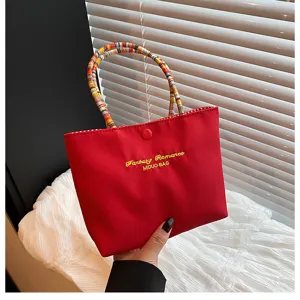 Vue détaillée du sac à main en toile style coréen, avec poignées tressées colorées et tissu rouge.