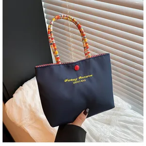 Vue détaillée du sac à main en toile de style coréen avec poignée tressée et bouton.