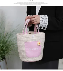 Detail view of straw woven tote bag with pink canvas pocket, cute flower charm and summer text.