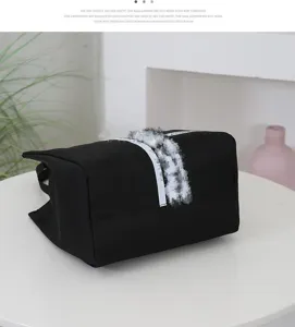 Detail view of a black canvas handbag, featuring a minimalist design and sturdy top handles.
