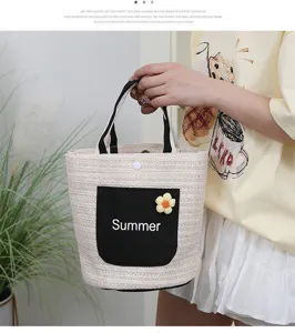 Detail view of woven straw tote bag featuring black handle and cute floral pocket.