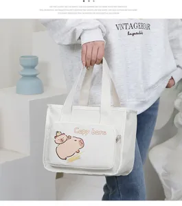 Canvas lunch bag detail showing cute capybara print front pocket, sturdy handles and zipper.