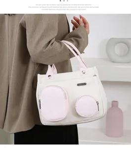 Stylish white canvas shoulder bag with pink pockets and top handles for daily casual use.