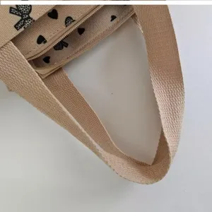 Canvas tote bag detail view showing sturdy handle zipper and cute bow heart print lining