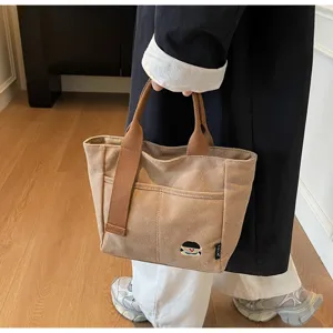 Canvas tote bag detail view showing thick fabric, sturdy handles, front pocket and cute embroidery.