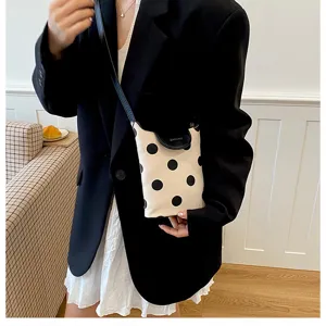 Detailed view of the stylish polka dot canvas shoulder bag with contrast black flap design.