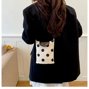 Detail view of a fresh polka dot linen shoulder bag worn outdoors in daily lifestyle scene.