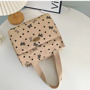 Close-up of beige canvas handbag with cute bow and heart print, ideal for daily commute.