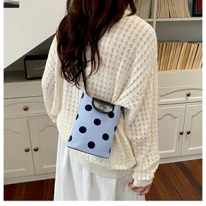 Detailed lifestyle view of a trendy polka dot linen shoulder bag with black leather flap.