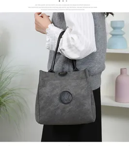 Detailed view of the textured grey bucket bag with dual handles and stylish front logo.