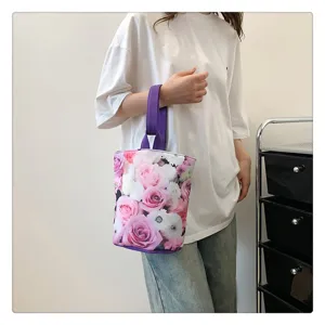 Detail shot of the floral print canvas bucket bag with purple handle, close-up lifestyle.