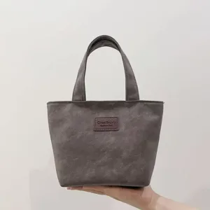 Close-up detail of the minimalist grey PU tote bag featuring sturdy handles and front label.
