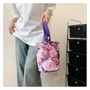 Detail view of the floral canvas bucket bag with purple handle, showing fresh pink rose pattern.