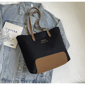 Detailed view of casual black canvas tote bag with brown leather handles and base patch.