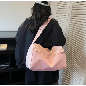 Detailed view of pink grid travel duffel bag worn across body, indoor lifestyle setting.
