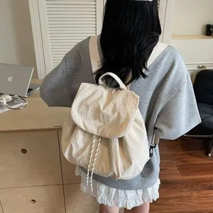 Detailed view of casual nylon backpack in beige, showing drawstring and flap design indoors.