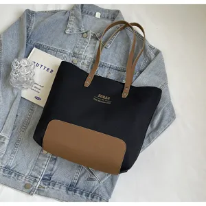 Detail view of minimalist canvas tote bag, featuring sturdy brown leather straps and contrast bottom.