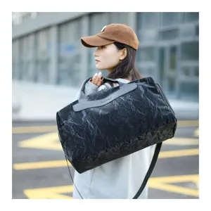 Detail view of the lightweight black travel duffel bag showing texture and handle.