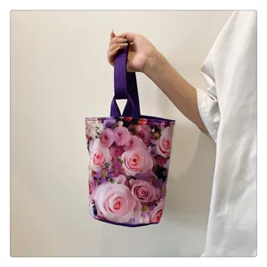 Chic canvas bucket handbag with beautiful pink rose floral print and purple handle details.