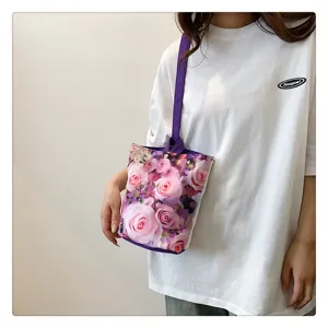 Closeup of the canvas bucket bag featuring a vibrant pink rose floral print and purple straps.
