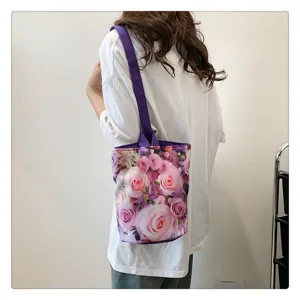 Detail shot of canvas bucket bag with floral rose print and purple shoulder strap in daily scene.