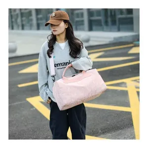 Outdoor scene detail showing a large capacity pink travel duffel bag held by a model.