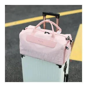 Pink travel duffel bag detail, showing waterproof fabric, sturdy handles and dual zippers.