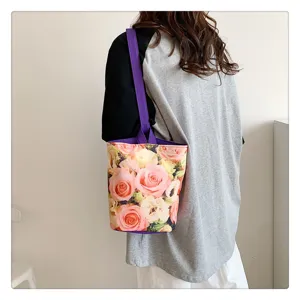 Detailed view of canvas bucket bag showing vibrant rose floral print and purple handles.