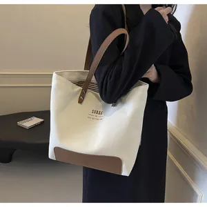 Minimalist canvas tote bag with leather bottom and handles, perfect for daily commute and casual use.