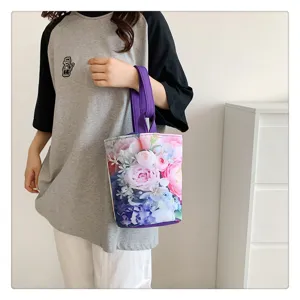 Detail view of the floral canvas bucket bag with purple handle, showing vibrant print.