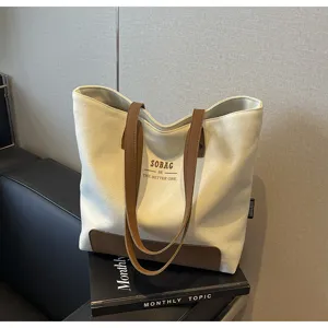 Canvas tote bag detail view showcasing durable fabric, brown leather handles, and front print.