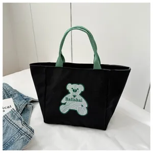 Detail shot of a black canvas tote bag with green handles and linear bear graphic print.