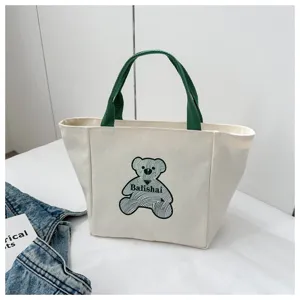 Canvas tote bag with green handles and cute bear graphic for casual daily shopping and travel use.