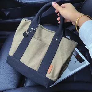 Canvas tote bag with contrast handles, front pocket and charm for daily casual use.