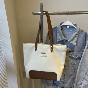Minimalist canvas tote bag with brown leather straps and base, casual commuter handbag.
