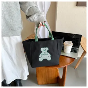 Stylish black canvas tote bag with green handles and cute bear design, perfect for daily use.