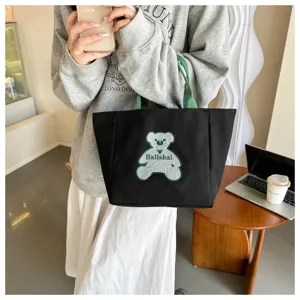 Fashionable black canvas tote bag for women, casual green handle shoulder dumpling bag daily use.