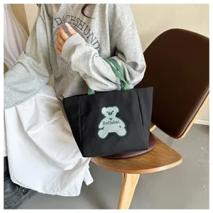 Black canvas tote bag with green handles and cute bear embroidery, casual daily handbag style.