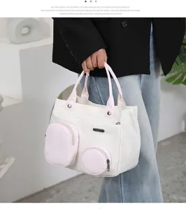 Detailed view of white and pink canvas tote bag, featuring cute front pockets and twin top handles.