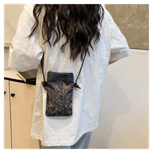 Detail view of the retro Chinese floral print crossbody phone bag worn by a model outdoors.