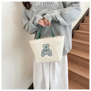 Casual canvas tote bag with cute bear print and green handles, perfect for daily fashion use.