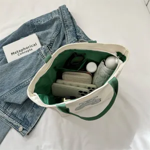 Casual canvas tote bag with green handles and large capacity multi-pocket interior storage.