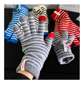Close-up detail of knitted striped gloves with touch screen fingertips for winter warmth.