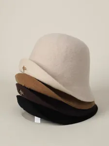 Close up detail shot of stacked wool felt bucket hats in assorted colors with metallic charms.