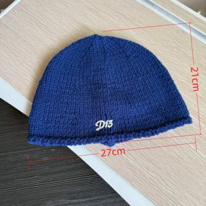 Dunkelblaue Strickmütze Detail mit 21cm Höhe und 27cm Breite sowie einer feinen D13-Stickerei.