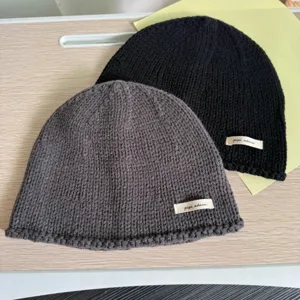 Nahaufnahme von weichen Strickmuetzen in Grau und Schwarz mit gewebtem Etikettendetail.