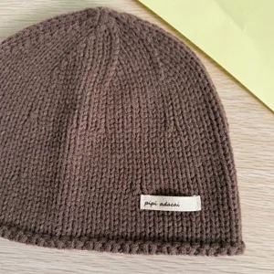 Braune Strickmütze Detail, warme Winterschutzkappe mit kleinem Etikett, lässige Alltagsbekleidung.