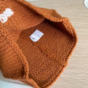 Detailansicht der inneren Textur und des Waschetiketts dieser braunen Strickmütze.