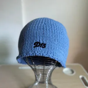 Detailansicht der blauen Strickmütze mit gestickten D13 Buchstaben und warmer Wolle für den Winter.