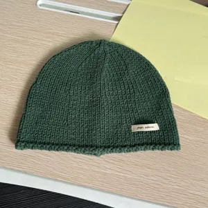Dunkelgrüne Strickmütze Detailansicht mit feiner Textur und kleinem Label für Damen.
